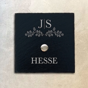 Può includere: Cartello per campanello in ardesia nera con le iniziali "JS" in bianco, un motivo floreale e il nome "HESSE" sotto il pulsante.