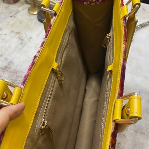 May include: Yellow tote bag with a floral patterned lining. The bag has two zippered pockets on the inside.