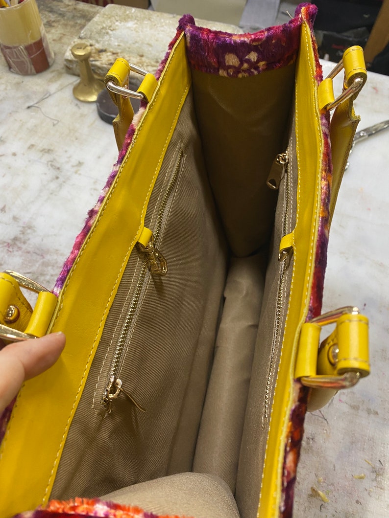 May include: Yellow tote bag with a floral patterned lining. The bag has two zippered pockets on the inside.