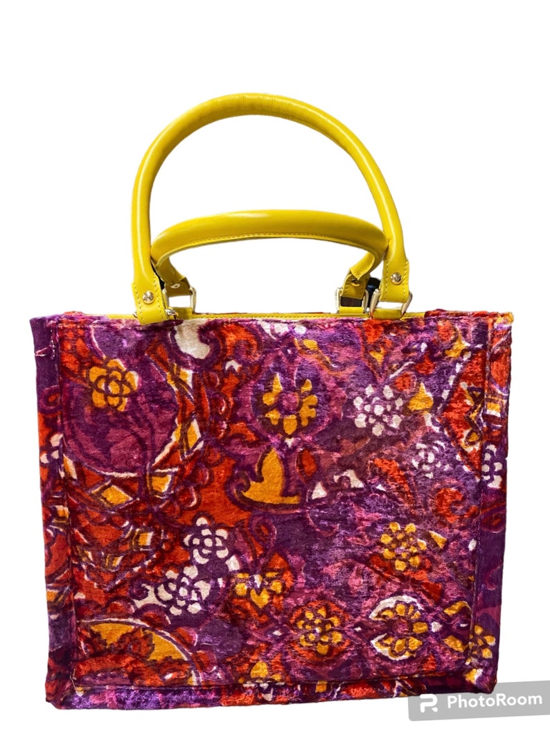 May include: A purple, red, and yellow floral patterned tote bag with a yellow leather handle.