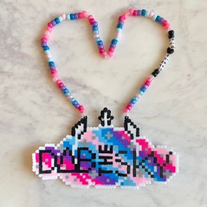 May include: A colorful beaded necklace with a pixelated charm that says "DIVE INTO THE SKY" and the words "DABIN STS" on the beaded chain.