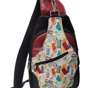 May include: Black and red sling bag with a license plate pattern on the front pocket. The bag has a black strap and a red leather top. The front pocket features license plates with various numbers and letters.