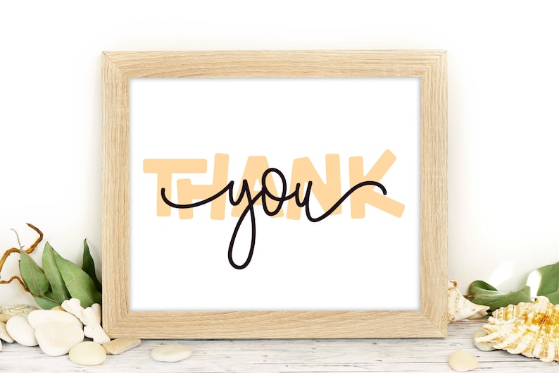 May include: A framed print with the text "THANK you" in a peach color with black cursive writing.