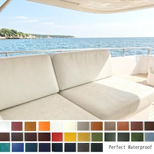 Könnte beinhalten: Cremefarbene Bootskissen auf einer Yacht, mit Blick auf das Meer und die Küste. Die Kissen sind rechteckig und scheinen aus einem strapazierfähigen, wasserdichten Material zu bestehen. Eine Farbpalette verschiedener Farbtöne wird darunter angezeigt. Der Text "Perfect Waterproof" ist sichtbar.