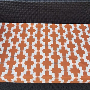 May include: A brown and white patterned cushion for an outdoor wicker sofa.