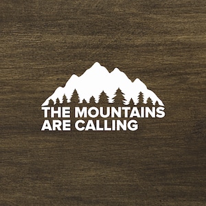 Puede incluir: Silueta blanca de una cordillera con árboles delante sobre un fondo de madera marrón. El texto "THE MOUNTAINS ARE CALLING" está debajo de la imagen.