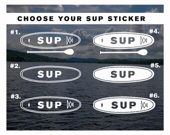 Op de afbeelding: Zes verschillende ontwerpen voor een stand-up paddleboard sticker. De stickers zijn wit met zwarte contouren en bevatten het woord "SUP" met verschillende ontwerpelementen. De stickers worden getoond op een achtergrond van een meer met bomen en wolken.