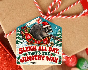 Puede incluir: Una etiqueta de regalo con forma de casa que muestra un mapache con gorro de Papá Noel en un trineo rojo lleno de regalos. La etiqueta incluye el texto "To:", "SLEIGH ALL DAY, THAT'S THE JIMOTHY WAY" y "From:", decorada con pinos verdes y acebo.