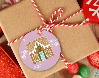 Puede incluir: Un regalo envuelto con una etiqueta redonda de color lavanda con un diseño de casa de jengibre y copos de nieve. La etiqueta tiene las palabras "PARA:" y "DE:" impresas. El regalo está atado con hilo rojo y blanco.