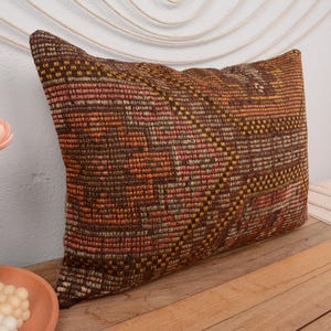 May include: A brown, orange, and cream patterned throw pillow with a woven texture.