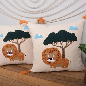 Funda de almohada con diseño de león de safari (40,6 x 40,6 cm), bordada, ideal para habitación infantil o guardería, con borlas naranjas.