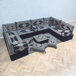 May include: A modular floor sofa set in deep navy blue featuring intricate geometric patterns in white, light blue, and gold. The set includes multiple backrests, corner pieces, floor cushions, and a matching rug, all with a consistent textile design.