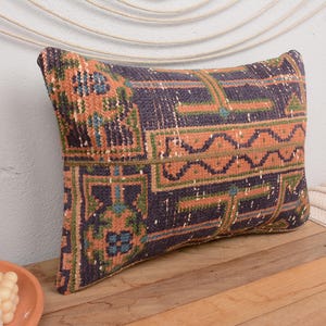 May include: A decorative cushion with a colourful geometric pattern in shades of blue, orange, green, and brown. The cushion is made of a woven fabric and has a rectangular shape.