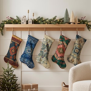 Puede incluir: Cinco calcetines navideños colgados de una repisa de madera, cada uno con un patrón tejido intrincado y distinto en colores variados que incluyen rojo intenso, azul marino, crema y verde esmeralda, junto a una guirnalda iluminada.