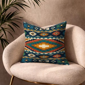 May include: A square throw pillow featuring a vibrant geometric pattern with horizontal bands of deep blue, burnt orange, mustard yellow, and teal. The design includes repeating diamond and stepped motifs across the entire fabric surface.