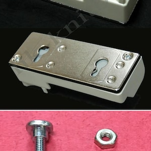 May include: White plastic row counter with three dials numbered 1, 2, and 3. The counter has a white plastic knob and a metal plate with two keyholes. The counter is accompanied by two silver metal screws and nuts.