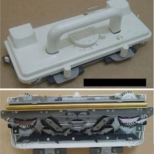 May include: A white plastic knitting machine with a handle and a dial. The machine is open to reveal the inner workings, including a gold metal bar and several gears.