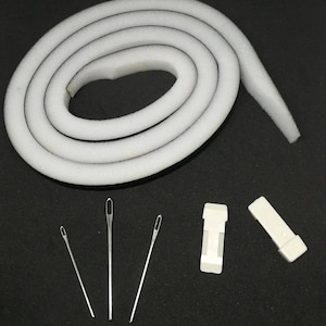 May include: A white foam piping cord with a black line running along the center, three silver needles, a white plastic clip, and a white plastic piece.