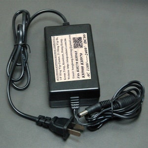 May include: Black power adapter with a black power cord and a black plug. The adapter has white text that reads "SUN CHEONG KNITTING MACHINE COMPANY LTD. 3/F Hing Yip Center, 31 Hing Yip St, Kwun Tong, Kowloon, Hong Kong. Website: http://shop.sckmcl.com.hk Email: hongkong.knitting@gmail.com Fits KH270 KH965 KH900 KH970 AC 110V~240V DC9V".