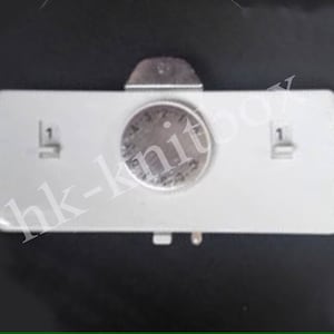 May include: A white plastic timer with a round dial and two buttons labeled "1". The dial has black markings and numbers.