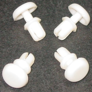 May include: Four white plastic push-in fasteners with a round head and a split pin. These fasteners are commonly used for attaching panels or trim.