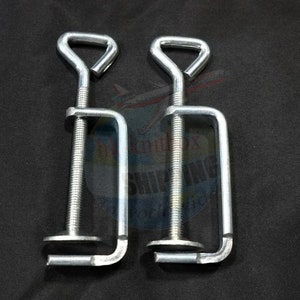 May include: Two silver metal clamps with a screw adjustment and a D-shaped handle. The clamps are designed for woodworking or other crafts.