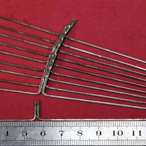 May include: A set of 10 silver knitting needles with a ruler measuring 15 inches. The needles are arranged in a fan shape with the tips of the needles pointing to the right.