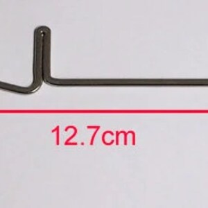 K&ouml;nnte beinhalten: Eine silberne Stricknadel mit einem Haken an einem Ende und einer Schlaufe am anderen. Die Nadel ist 12,7 cm lang.