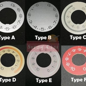 Puede incluir: Seis tipos diferentes de diales de máquina de coser, etiquetados de la A a la F. Los diales son circulares y tienen números del 0 al 10 impresos en ellos. Los diales son de diferentes colores, incluyendo plata, gris, beige y rojo.