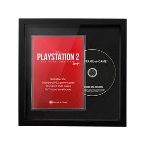 May include: A black framed display featuring a red PlayStation 2 game case and a game disc. The game case has the text "THE PLAYSTATION 2" and "USE YOUR OWN GAME". The disc has the text "FRAME-A-GAME".