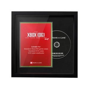 May include: A black framed display case featuring a red and green insert with the text "THE XBOX (OG)" and "USE YOUR OWN GAME". A game disc is visible on the right. The display is suitable for standard Xbox/360 game cases, DVD cases, and DVD sized steelbooks.