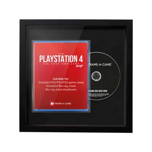 May include: A black framed display featuring a PlayStation 4 game case and a disc. The game case is red with white text that reads "PLAYSTATION 4" and "USE YOUR OWN GAME". The disc has the text "FRAME-A-GAME" and "GAME DISC GOES HERE".