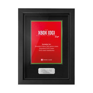 May include: A black framed display featuring a red insert with the text "THE XBOX (OG)". The display is suitable for standard Xbox/360 game cases, DVD cases, and DVD-sized steelbooks. The frame includes a small silver nameplate.