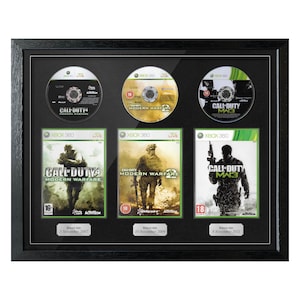 Puede incluir: Enmarcado con tres juegos de Call of Duty para Xbox 360. Los juegos son "Modern Warfare 4", "Modern Warfare 2" y "MW3". El marco negro muestra las portadas y los discos, con los títulos y fechas de lanzamiento.