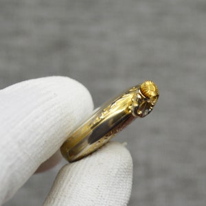 Peut inclure: Une montre de poche dor&eacute;e avec un design orn&eacute; et une couronne ronde dor&eacute;e.