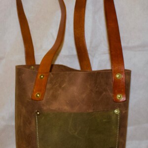 Cartera de cuero estilo tote para colgar al hombro, hecha a mano. 8” de ancho, 11” de alto y 4” de grosor, con asas de 14”.