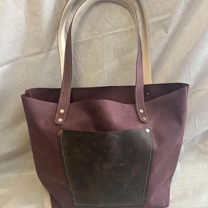Cartera de cuero estilo tote para colgar al hombro, hecha a mano. 8” de ancho, 11” de alto y 4” de grosor, con asas de 14”.