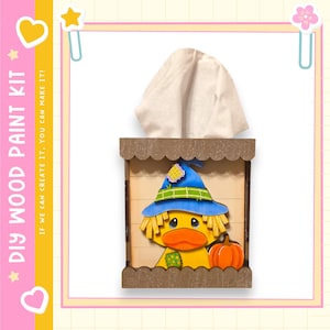 May include: DIY wood paint kit featuring a wooden tissue box with a cartoon duck wearing a blue hat and holding an orange pumpkin. The tissue box has a scalloped edge and is filled with white tissues. Text on the side reads: DIY WOOD PAINT KIT, IF WE CAN CREATE IT, YOU CAN MAKE IT!