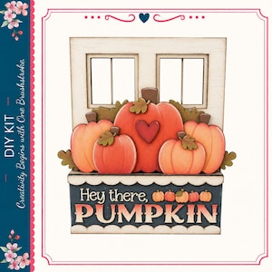 May include: A wooden DIY kit featuring a window frame with a planter box filled with orange pumpkins. The center pumpkin has a red heart. The planter box is dark blue with the text "Hey there, PUMPKIN" in white and orange lettering.