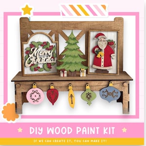 May include: A wooden DIY Christmas paint kit featuring a shelf with decorative ornaments and framed cutouts of a Christmas tree, Santa Claus, and a "Merry Christmas" sign. Includes ornaments in various shapes and colors.