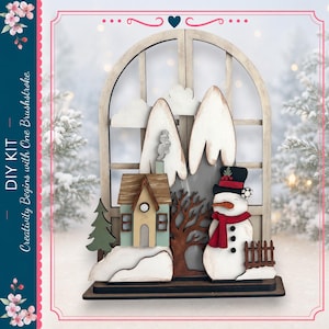 May include: A DIY kit featuring a layered wooden winter scene with an arched window frame, a light green house, a snowman wearing a black hat and red scarf, a brown tree, a green pine tree, and white snow-capped mountains with smoke.