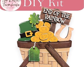 May include: A DIY kit featuring a wooden basket filled with St. Patrick's Day themed cutouts including a green hat, a four-leaf clover, gold coins, a horseshoe, and a sign that reads END OF THE RAINBOW. A small green tag reads LUCKY YOU.