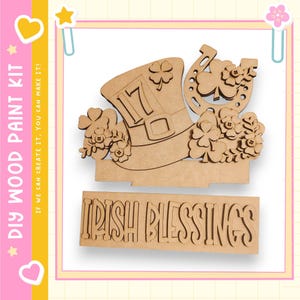 May include: A DIY wood paint kit featuring a leprechaun hat with the number 17, a horseshoe, and shamrocks. The words "IRISH BLESSINGS" are below the hat. The kit includes the text "DIY WOOD PAINT KIT" and "IF WE CAN CREATE IT, YOU CAN MAKE IT!"