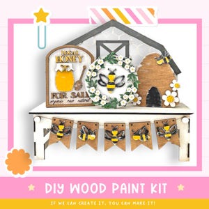 May include: DIY wood paint kit featuring a bee-themed design. The kit includes a sign that says "Local Honey For Sale", a beehive, a wreath with a bee, and a banner with bees.