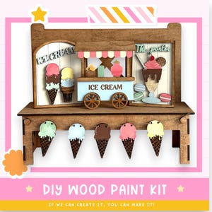 May include: A wooden DIY paint kit featuring an ice cream parlor and cones. The kit includes a miniature ice cream cart with the words "ICE CREAM" and various ice cream cones. The text "DIY WOOD PAINT KIT" is also visible.