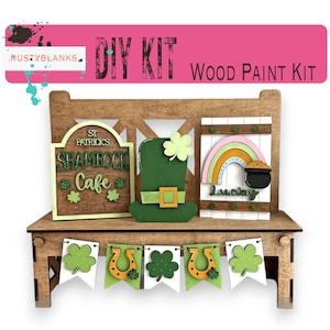 May include: DIY wood paint kit featuring a wooden bench with a shamrock cafe sign, a leprechaun hat, a rainbow with a pot of gold, and a banner with shamrocks and horseshoes. The kit includes all the necessary pieces to create a festive St. Patrick's Day decoration.