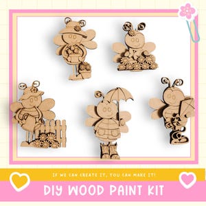 May include: A collection of five unfinished wooden bee-shaped figures, each with unique accessories like a hat, umbrella, or kite. The figures are part of a DIY wood paint kit, with the text "IF WE CAN CREATE IT, YOU CAN MAKE IT!" and "DIY WOOD PAINT KIT".
