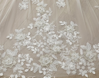 May include: White tulle fabric with delicate floral embroidery and 3D flowers. The flowers are made of white fabric and have a pearl-like center. The fabric is sheer and has a soft, flowing texture.