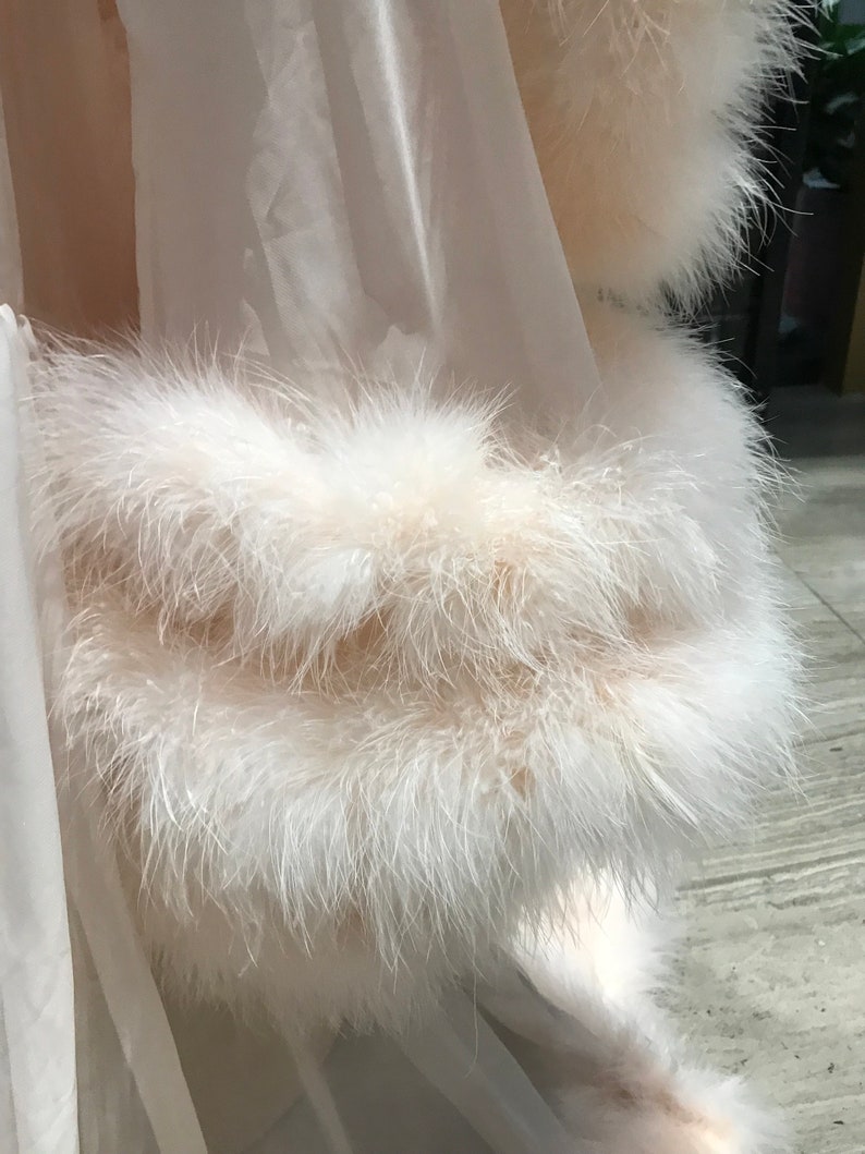 Puede incluir: Una bata blanca transparente con un ribete de plumas blancas y esponjosas alrededor de los bordes.