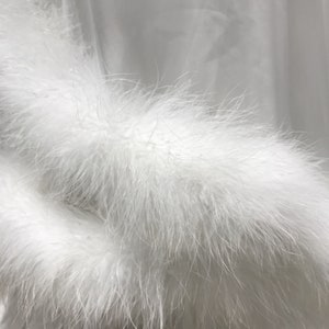 May include: White satin robe with a fluffy white feather trim around the cuffs.